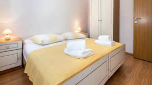 A neatly arranged bedroom with a bed, bedside lamps, a wardrobe, and a door. - Apartments Gulin - One Bedroom Apartment with Terrace and Sea View (Šibenik)