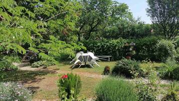 A garden with a metal sculpture, various plants, and a pathway.