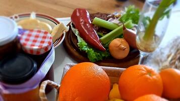 A wooden table with a variety of fruits and vegetables, including oranges and a basket of lemons.
