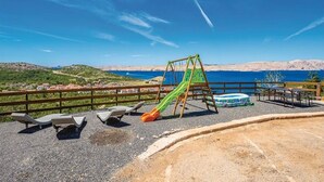 A playground with a slide and swing set, overlooking a coastal landscape. - Apartments Villa Kim - One bedroom Apartment with Terrace and Sea View (Jablanac)