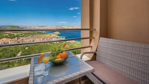 A balcony with a table, a bowl of fruit, and a glass of orange juice. - Apartments Villa Kim - One bedroom Apartment with Terrace and Sea View (Jablanac)