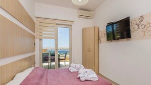 Un dormitorio con cama, televisor, armario y balcón con vistas.