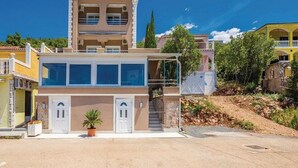 A two-story building with a balcony, a small garden area with a potted plant, and a clear blue sky. - Apartments Villa Kim - Double Room with Terrace (Jablanac)