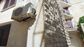 Ein Gebäude aus Stein mit Klimaanlagen, einem Balkon mit Metallgeländer und einer Tür.
