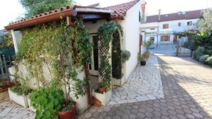 A small house with a tiled roof, a stone-paved courtyard, and potted plants. - Apartments Frane - One Bedroom Apartment with Terrace (Rovinj)