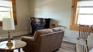 Una sala de estar con un sofá marrón, una mesa de centro de madera, una chimenea y una mesa de comedor con sillas.