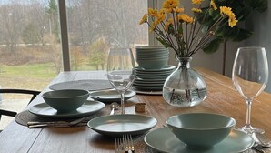 A dining table set with plates, bowls, cutlery, and a vase with yellow flowers. - Equestrian Charm near Torch Lake: Two homes in one! (Rapid City)