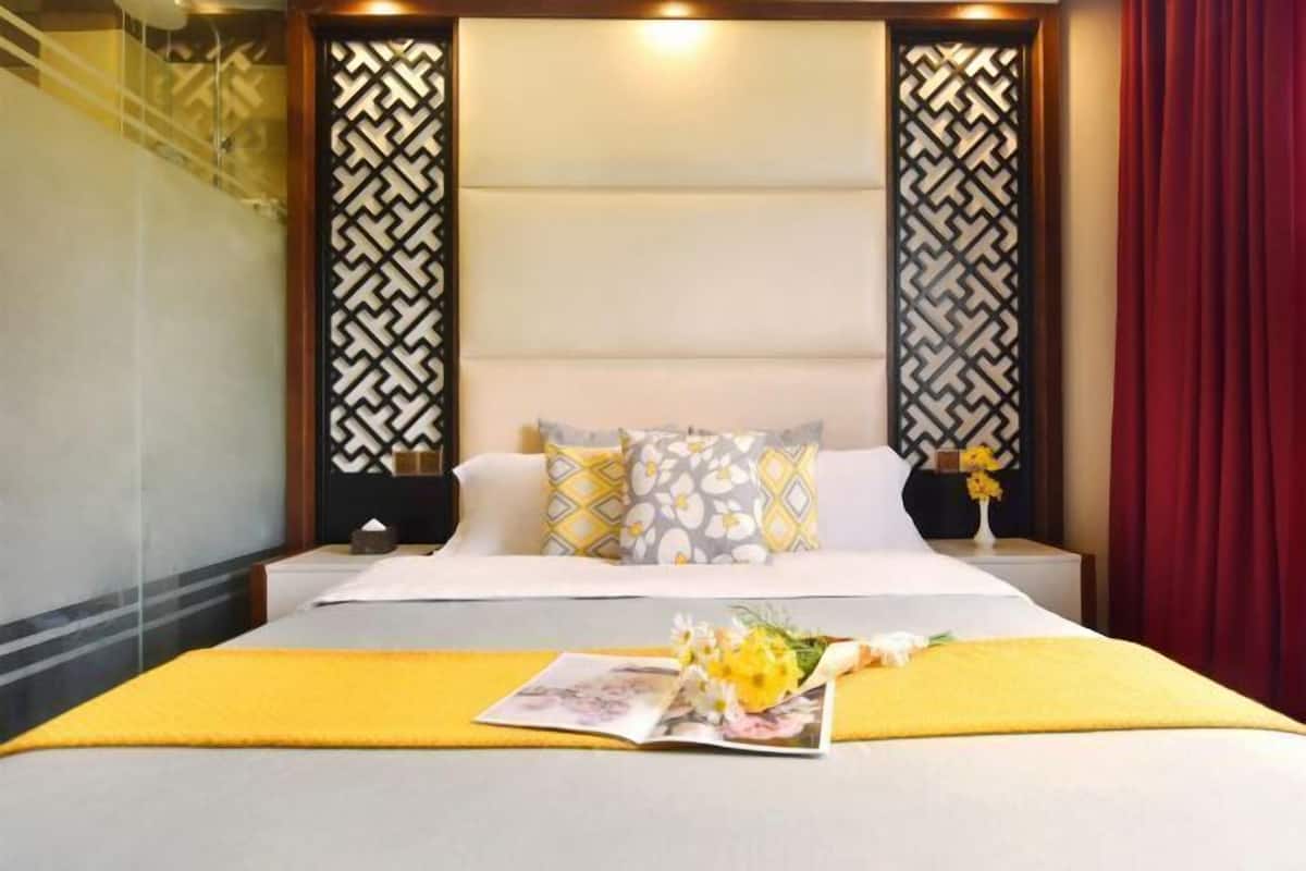 A hotel room with a bed, nightstands, a magazine, and a bouquet of flowers.