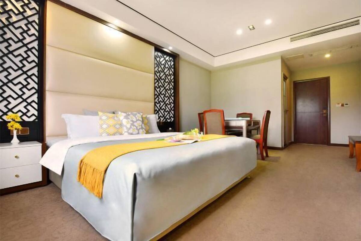 A hotel room with a large bed, a desk, and a chair.