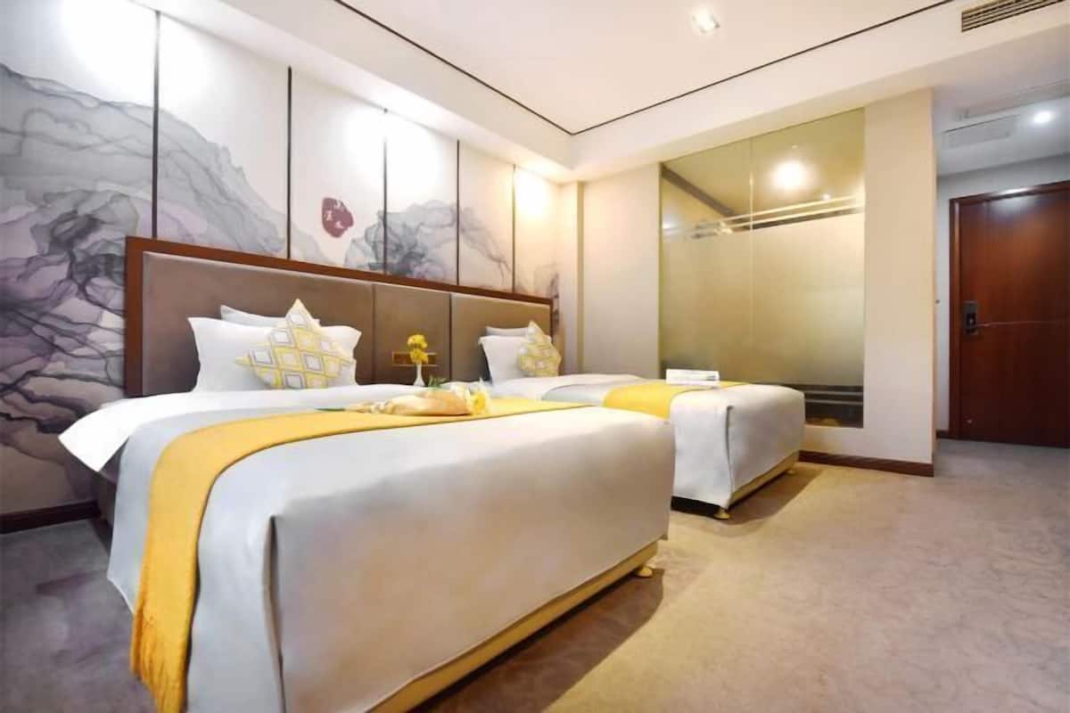 A hotel room with two beds, a large mirror, and a door.