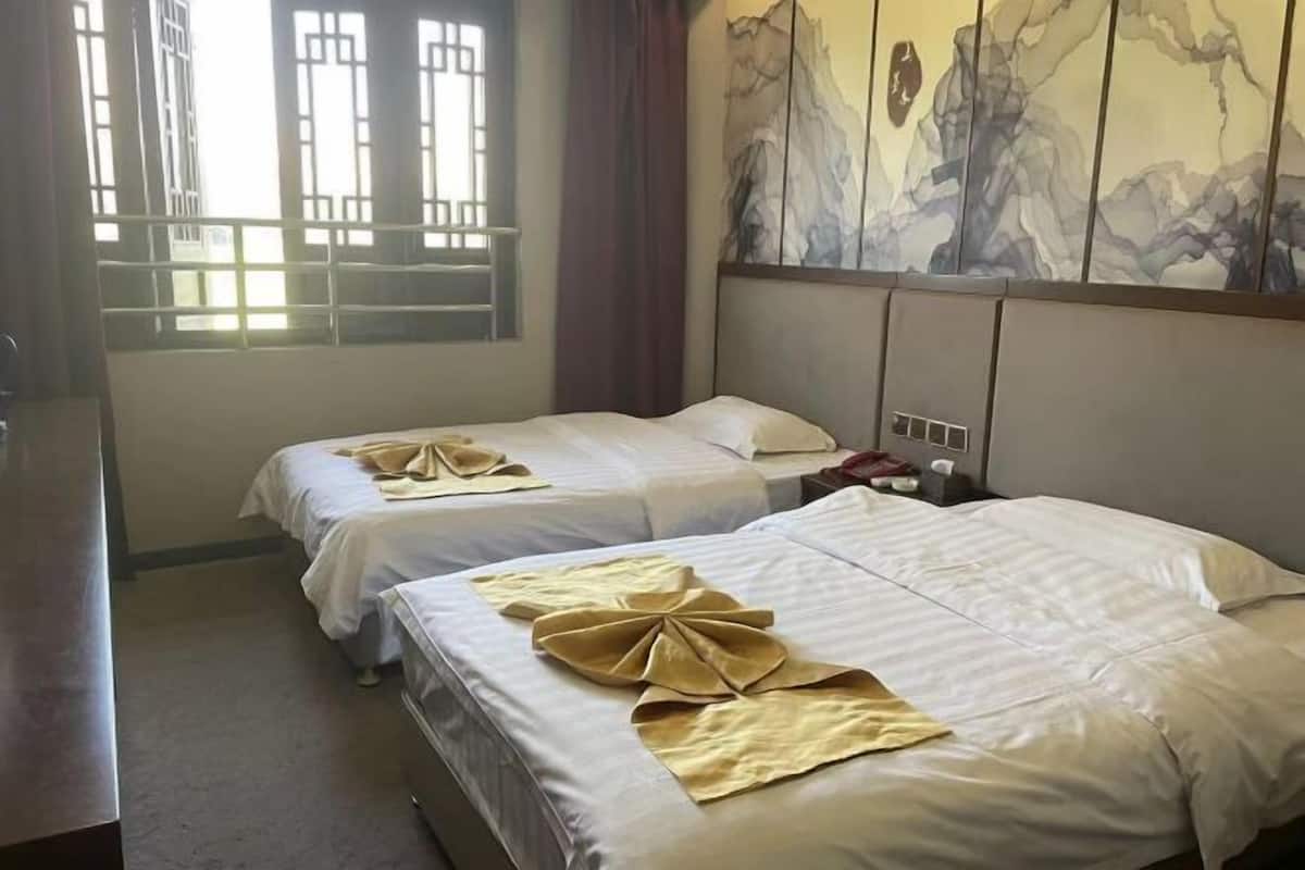 A hotel room with two beds, each with neatly arranged towels.