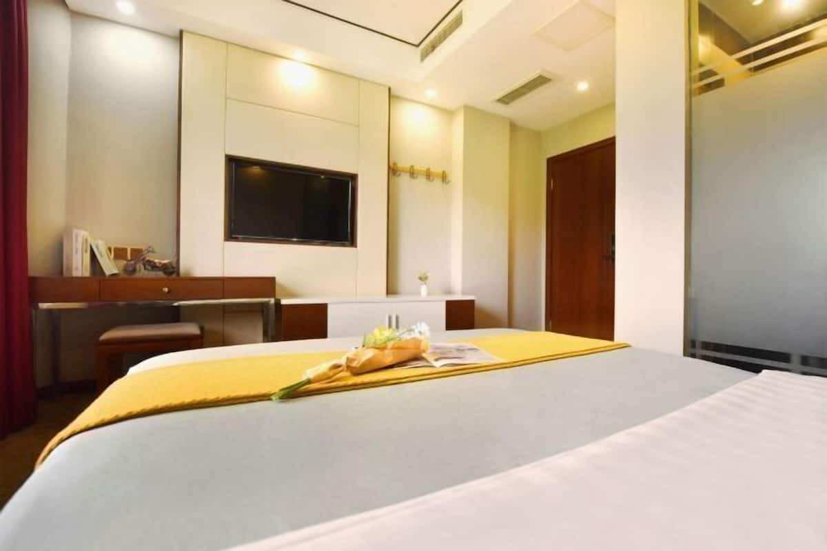 A hotel room with a bed, a desk, a television, and a window.