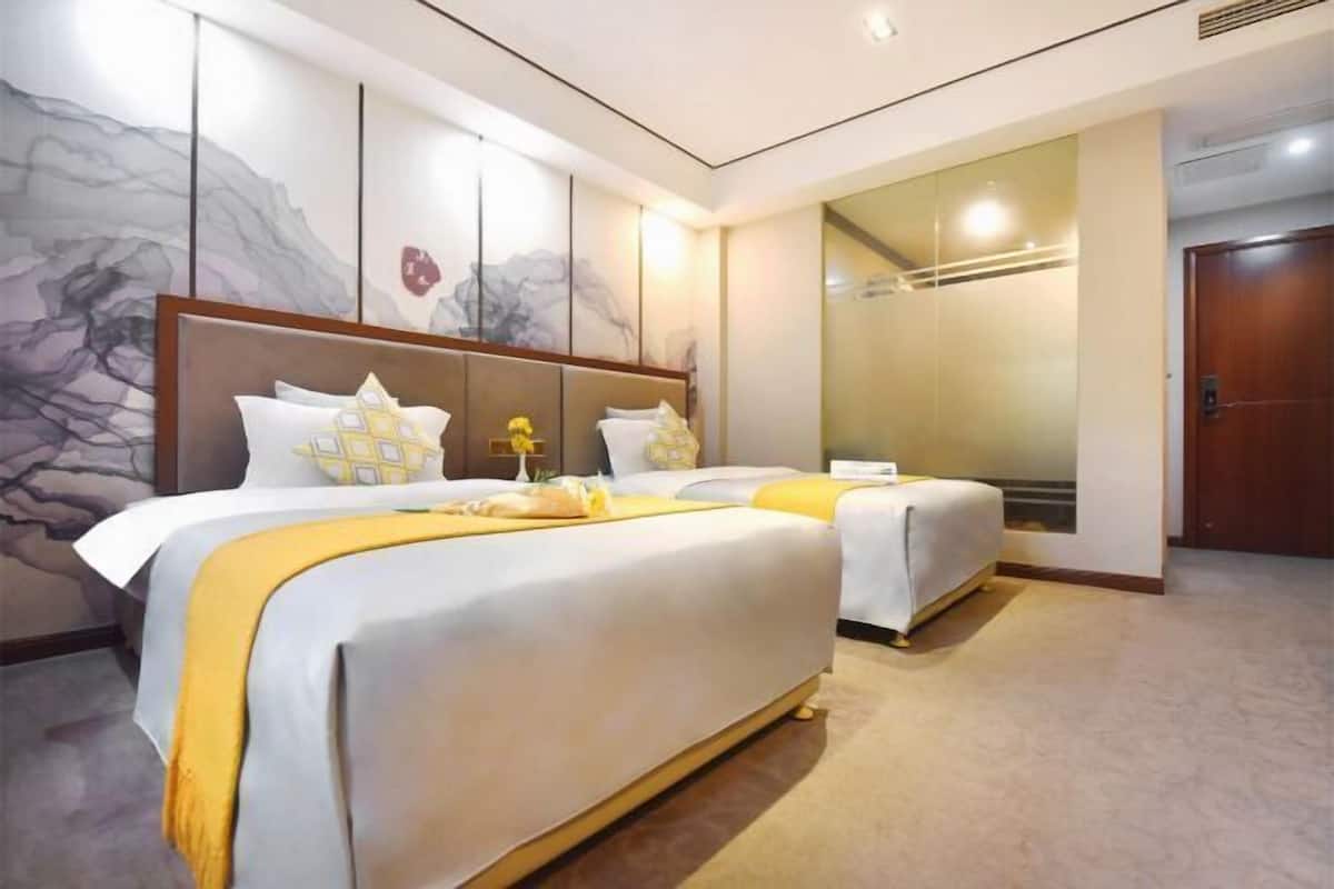 A hotel room with two beds, a large mirror, and a door.
