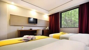 Une chambre d’hôtel avec deux lits, un bureau, une télévision et une fenêtre avec des rideaux.