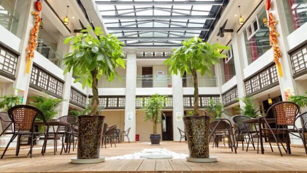 Un vaste atrium intérieur doté d’une verrière, de plusieurs niveaux et de plantes en pot.