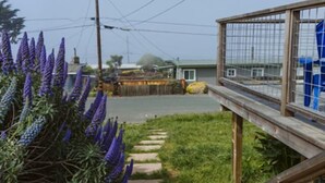 Un chemin menant à une maison dotée d’un porche entouré d’une clôture.