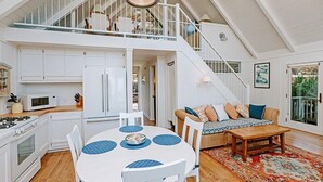 Una cocina amplia con armarios blancos, una mesa de comedor con individuales azules y una escalera que sube a un nivel superior.