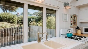 Una cocina con un lavamanos doble, una estufa a gas y vistas al exterior gracias a amplios ventanales.