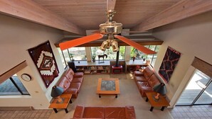 A spacious living room with leather sofas, a coffee table, and a ceiling fan.