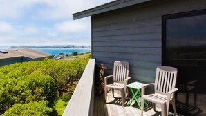 A balcony with two white chairs, a small table, and a view of a body of water and hills. - Boccabella - Quite south side location, expansive views. (Bodega Bay)