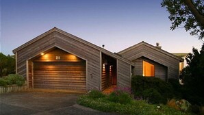 A modern two-car garage with a sloped roof, wooden siding, and a well-lit entrance. - Boccabella - Quite south side location, expansive views. (Bodega Bay)