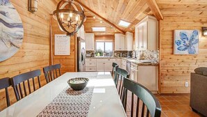 A wooden interior with a dining table, chairs, a chandelier, and a kitchen area. - Condors Nest - 10th green w/ocean views , . (Bodega Bay)