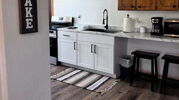 Eine moderne Küche mit weißen Schränken, einer Holz Arbeitsplatte und einer Spritzschutzwand.