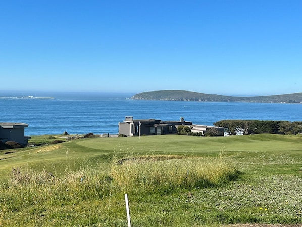 Une propriété située sur la côte, dotée d’une zone herbeuse, d’un petit bâtiment et offrant une vue sur la mer.