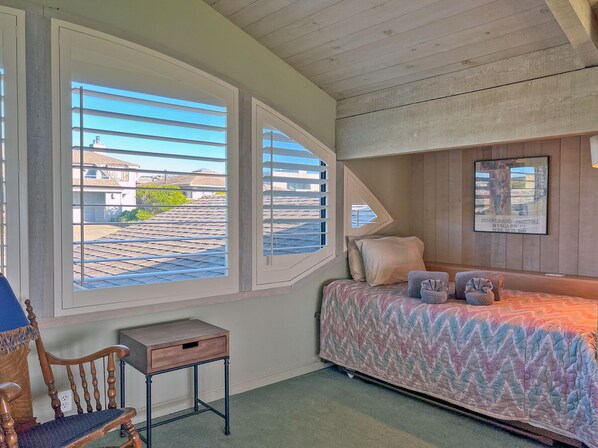 A bedroom with a bed, a chair, a small table, and a window with blinds. - 19th Hole - Spectacular ocean views, front line Bodega Harbour, 18th fairway (Bodega Bay)