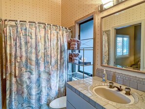 A bathroom with a shower curtain, a toilet, a sink with a mirror, and a towel rack with towels.