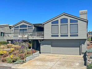 A modern two-story house with a garage, a balcony, and a well-maintained garden.