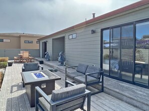 A modern outdoor patio with a fire pit, seating, and decorative statues.