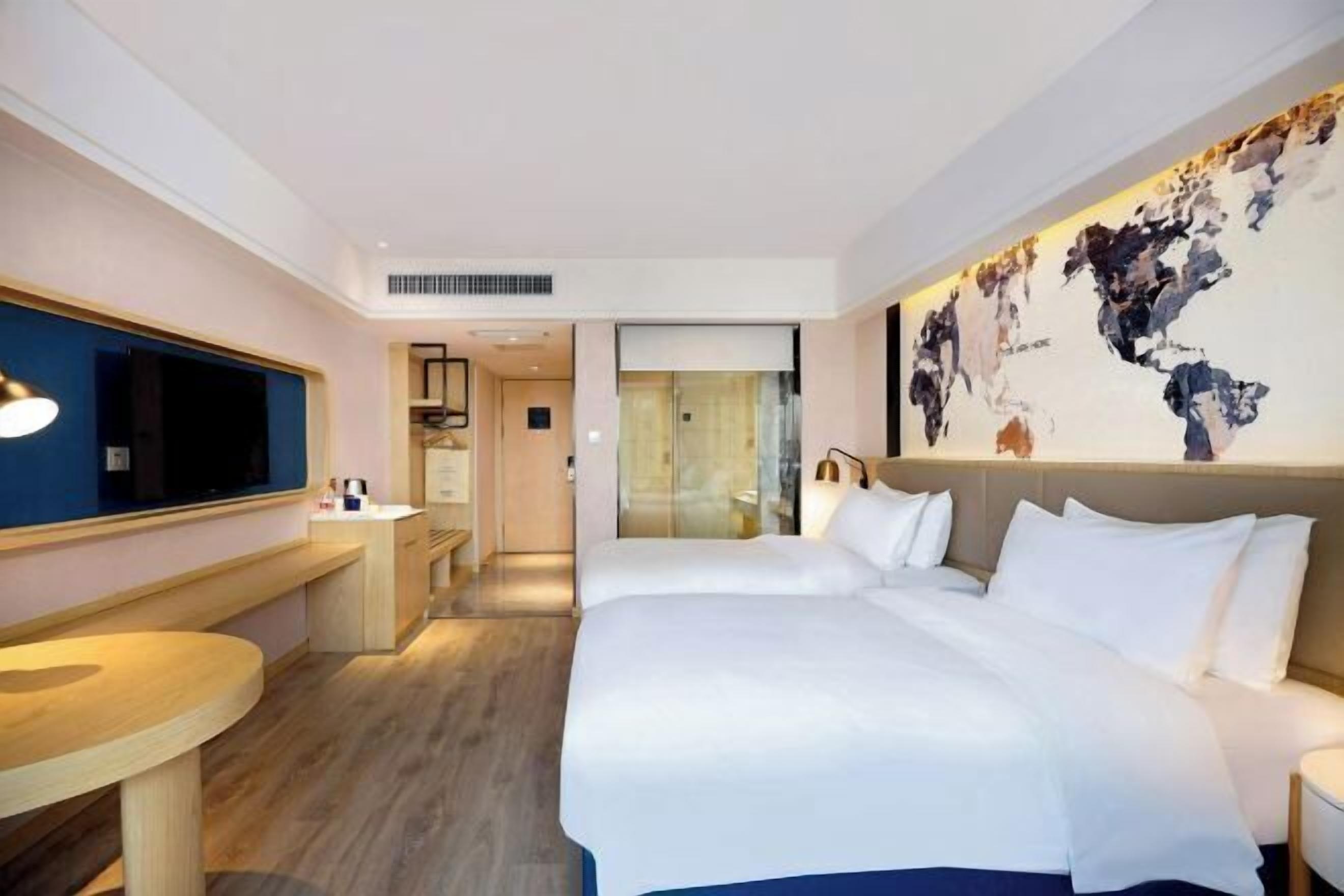 A hotel room with a large bed, a desk, a chair, and a television.