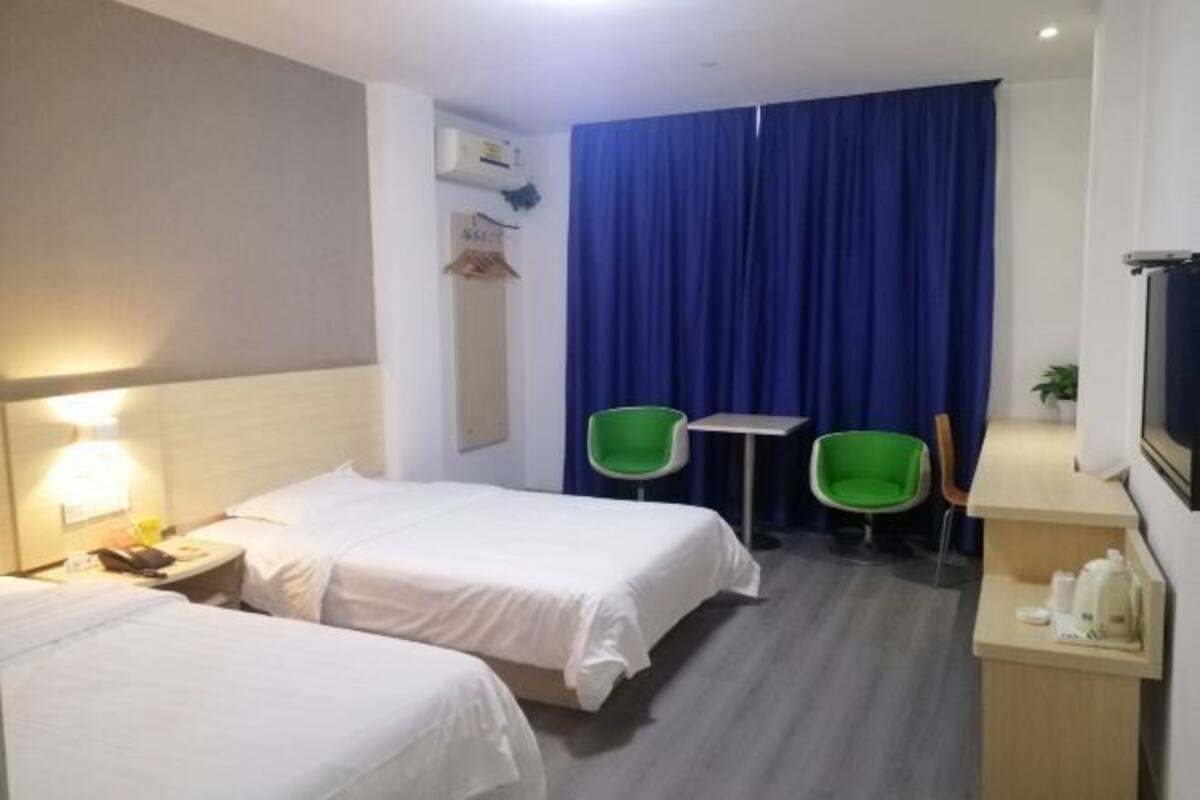 Habitació d'hotel amb dos llits, una taula de treball, una cadira i un televisor.