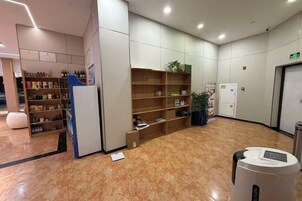 Un vestíbulo con una recepción, un quiosco de autoservicio y una zona de estar con una máquina de café.