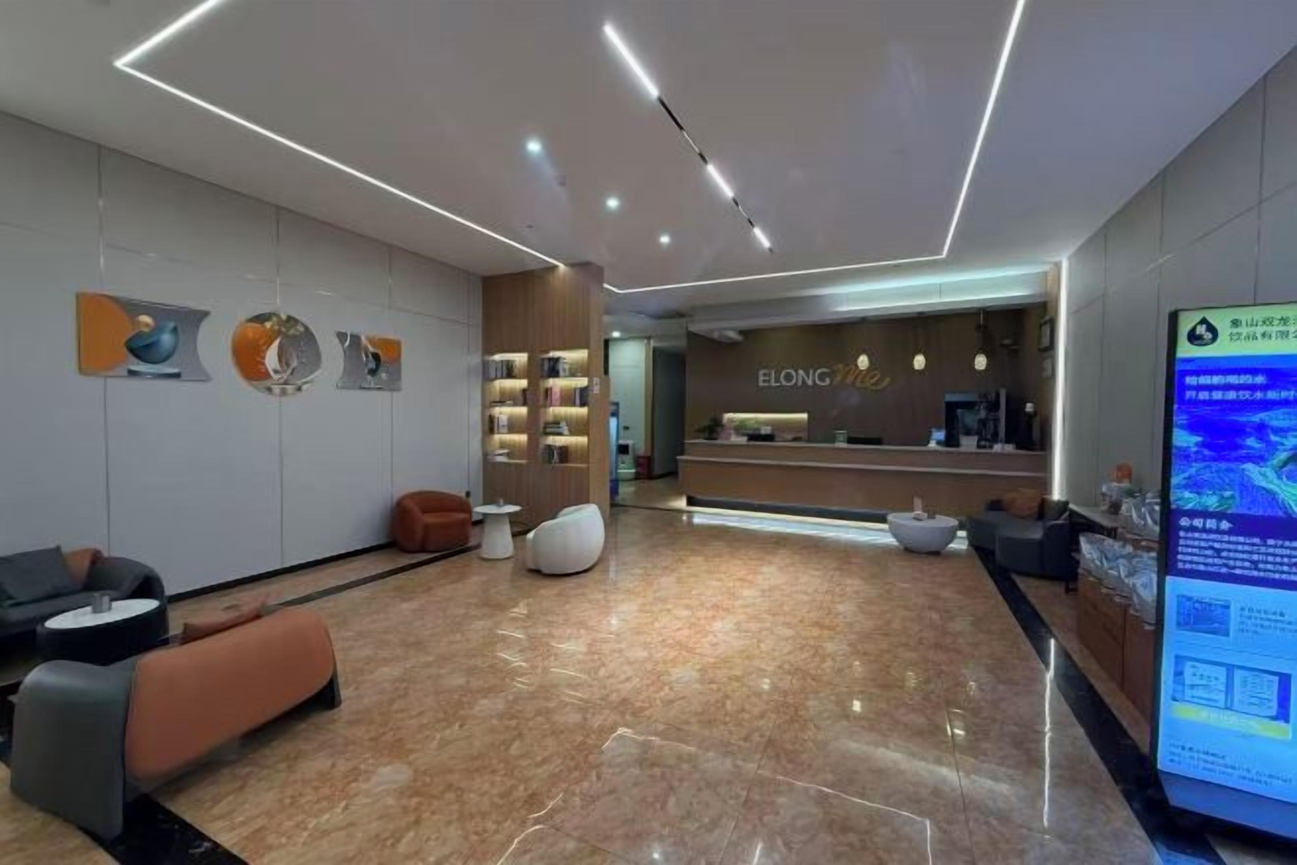 A modern reception area with a reception desk, seating area, and a digital information board.