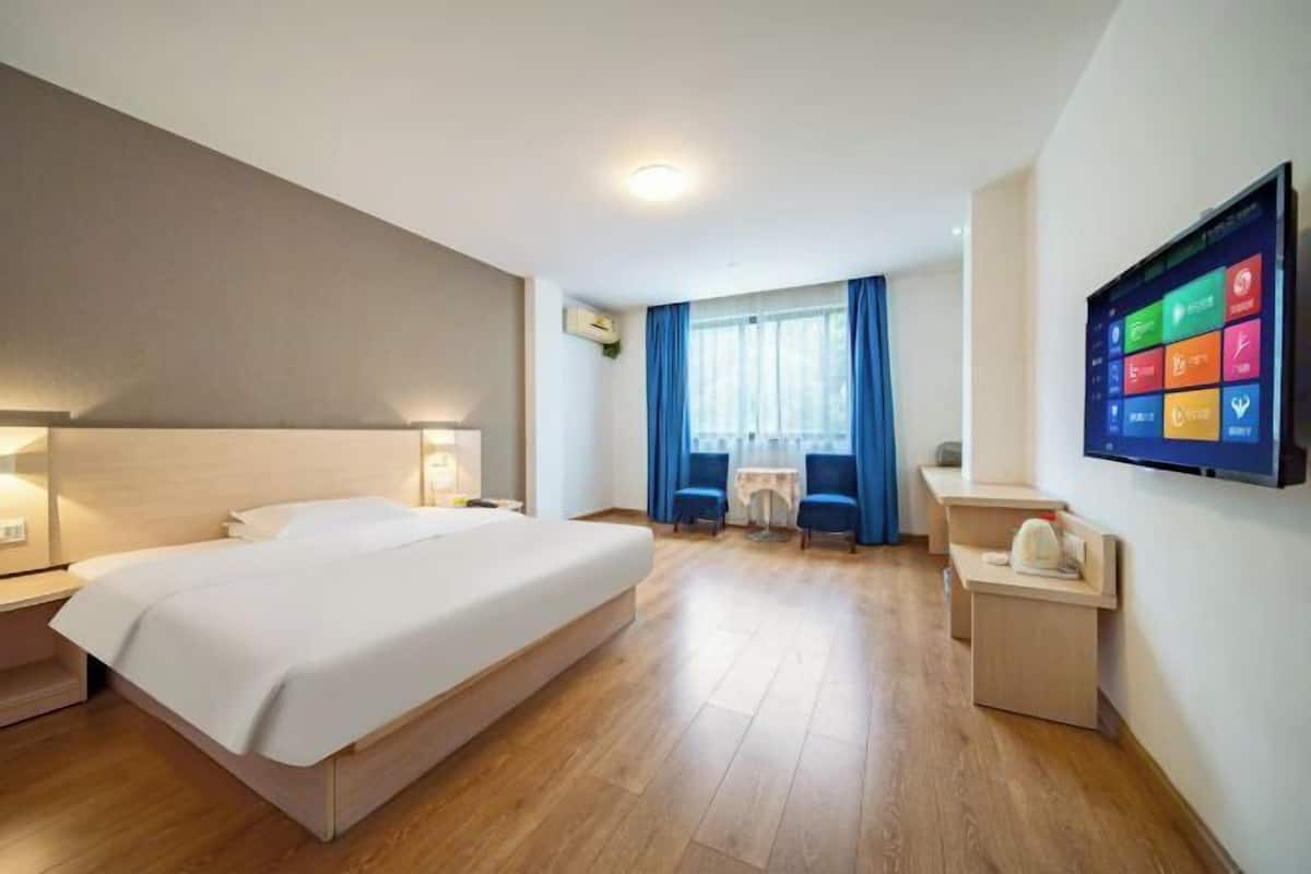 Habitació d'hotel amb llit, taules de nit, televisió, escriptori i cadira.