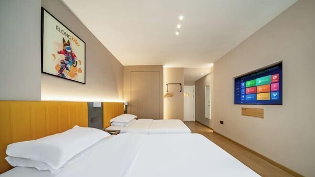 Ein Hotelzimmer mit zwei Betten, einem Fernseher an der Wand und einem Bild.