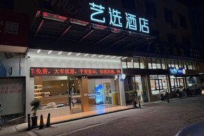A hotel with a prominent illuminated sign, a storefront with a red awning, and a visible entrance. - Yixuan Hotel (Ningbo Xiangshan People's Square) (Xiangshan)