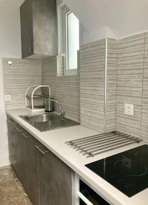 A modern kitchen with a stainless steel sink, a built-in stove, and a wooden backsplash. - 2-Storey Cycladic House In Old Town Sleeps 20 (Paros)