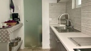 Cuina compacta amb un rentaplat, una cafetera i una petita zona d'emmagatzematge amb olis.