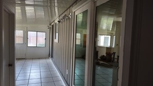 A corridor with sliding glass doors, tiled flooring, and a ceiling with horizontal slats. - House with a King Size Bed, in Desirable Rincon Valley, close to St Helena (Santa Rosa)