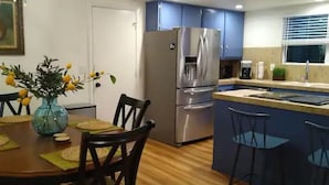 A compact kitchen with a refrigerator, a sink, and a dining area with a table and chairs. - House with a King Size Bed, in Desirable Rincon Valley, close to St Helena (Santa Rosa)