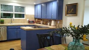 A compact kitchen with blue cabinets, a small island, a toaster, and a vase with lemons. - House with a King Size Bed, in Desirable Rincon Valley, close to St Helena (Santa Rosa)