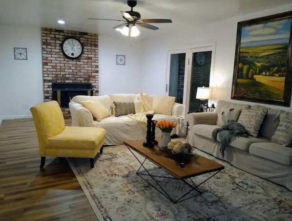 Relax in a stylish living room with a brick accent wall, comfortable seating area, and a warm fireplace.