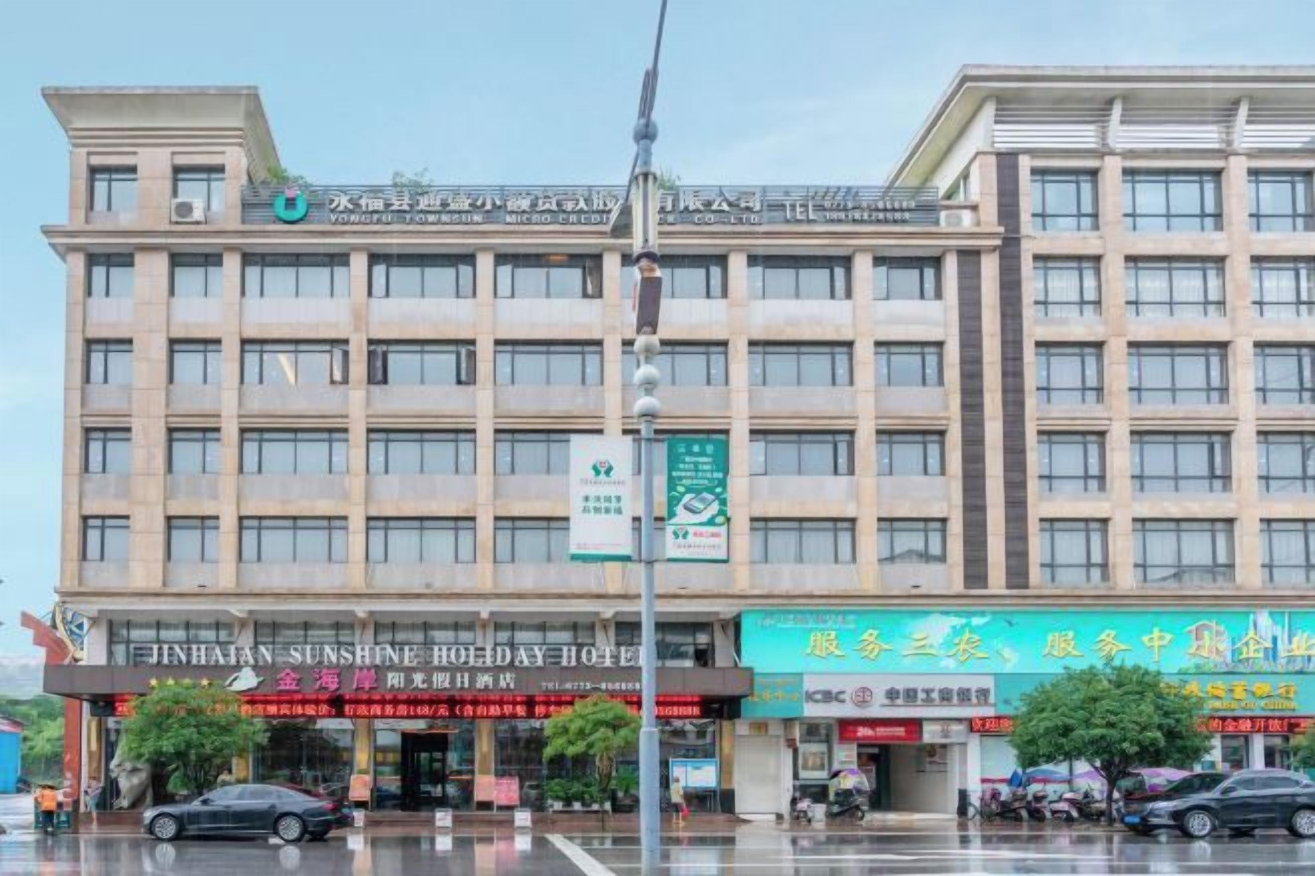 Un hotel de varios pisos con un letrero llamativo del Hotel Jinhan Sunshine Holiday.