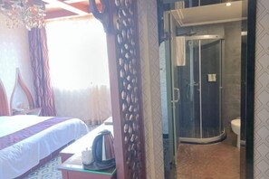 Habitación de hotel con cama, escritorio con hervidor, zona de ducha y retrete.