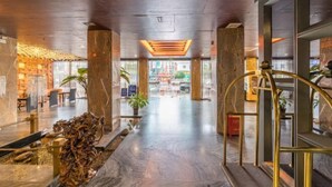 Un vestíbulo amplio con suelo de mármol, grandes columnas y una escalera central.