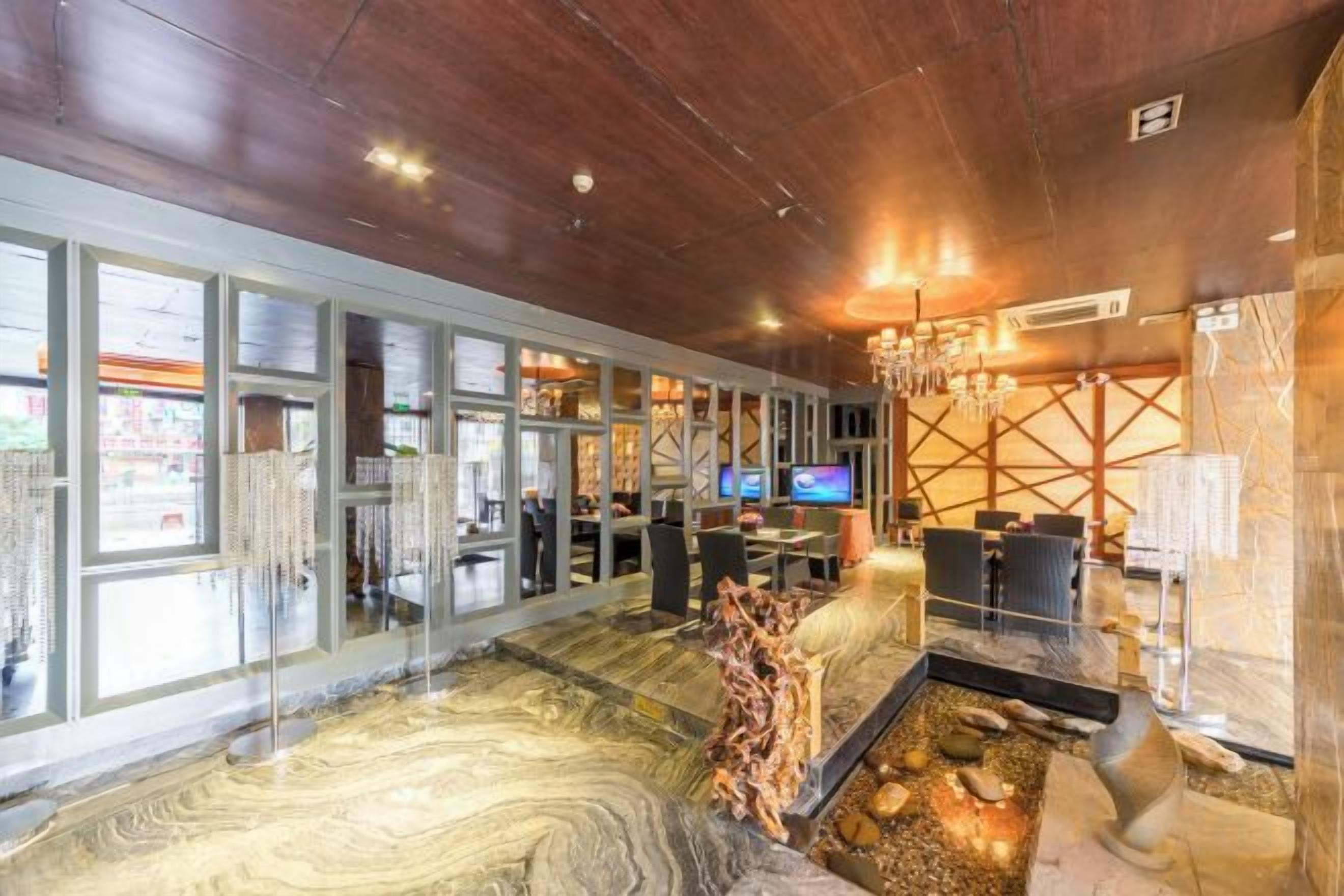 A hotel lobby with a marble floor, a reception desk, and a television.