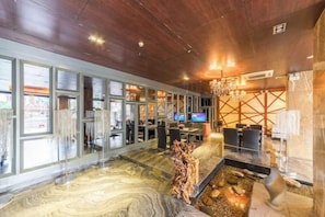 A hotel lobby with a marble floor, a reception desk, and a television.